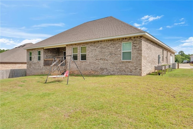back of property with a lawn, brick siding, and a shingled roof