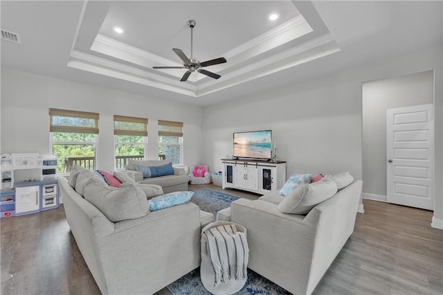 living room featuring ceiling fan, a raised ceiling, crown molding, and visible vents
