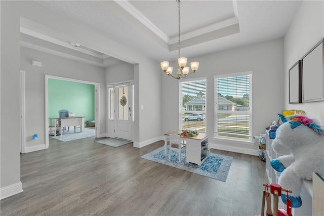 dining room with a tray ceiling, baseboards, ornamental molding, a chandelier, and wood finished floors