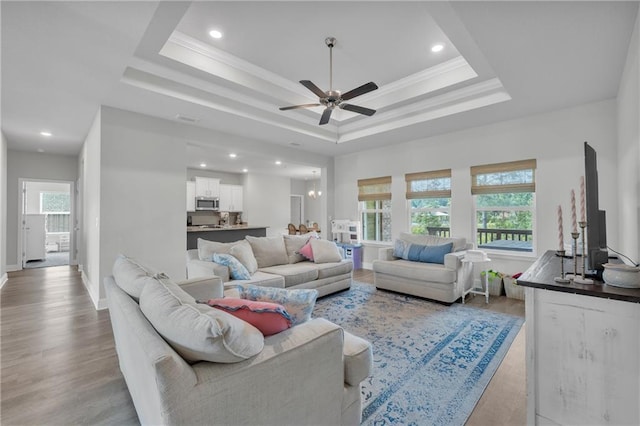living room with light wood-style flooring, baseboards, a raised ceiling, ceiling fan, and recessed lighting