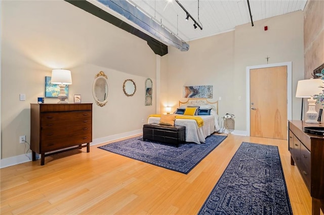 bedroom with a high ceiling, track lighting, and light hardwood / wood-style floors