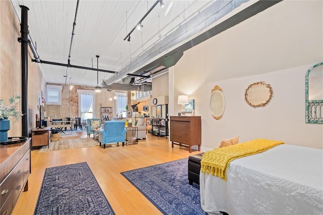 bedroom with track lighting, light hardwood / wood-style floors, and a high ceiling