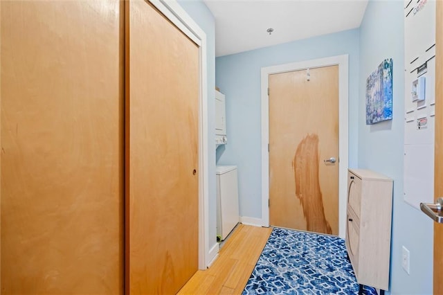 hallway featuring stacked washer / drying machine and light wood-type flooring