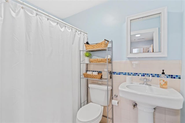 bathroom with tile walls, curtained shower, and toilet