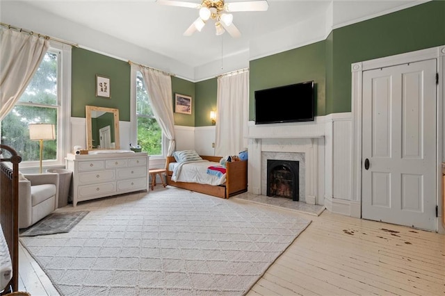 206 George St, Mobile, AL 36604 - bedroom featuring hardwood / wood-style floors, wainscoting, a decorative wall, a premium fireplace, and a ceiling fan