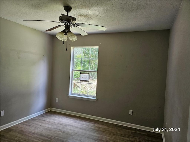 spare room featuring dark wood-type flooring, a textured ceiling, and ceiling fan