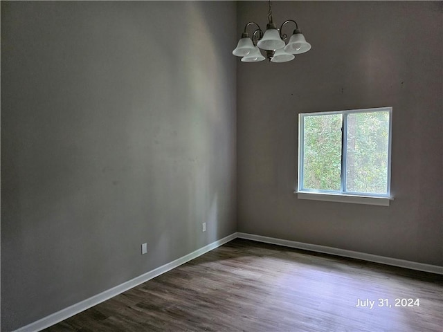 spare room with hardwood / wood-style flooring and a chandelier