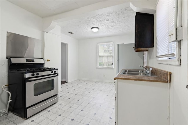 kitchen with a textured ceiling, sink, and stainless steel gas range