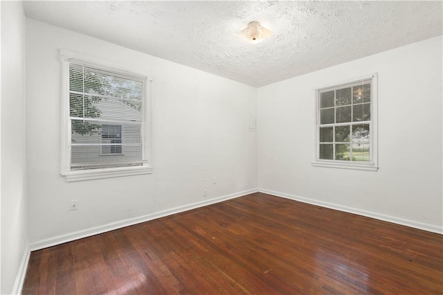 spare room with a textured ceiling and dark hardwood / wood-style flooring