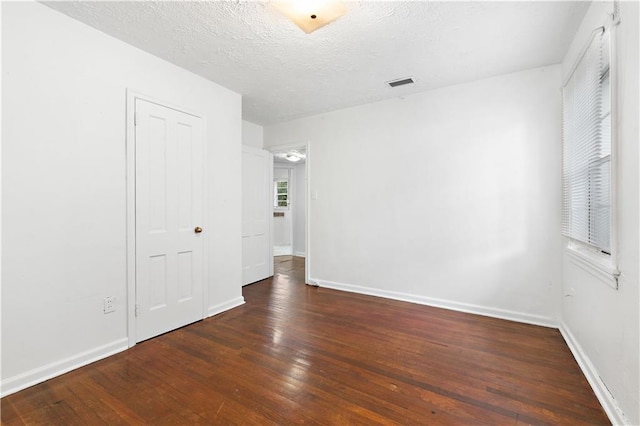 spare room featuring dark hardwood / wood-style flooring and a textured ceiling