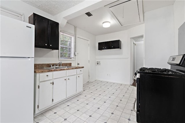 kitchen with white cabinetry, sink, black gas stove, white fridge, and a textured ceiling