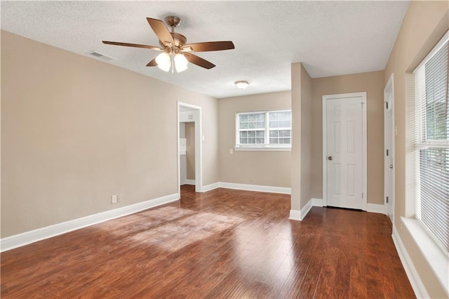 spare room with a textured ceiling, dark hardwood / wood-style flooring, and ceiling fan