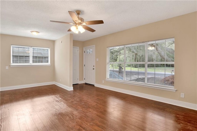 empty room with ceiling fan, a textured ceiling, and dark hardwood / wood-style floors