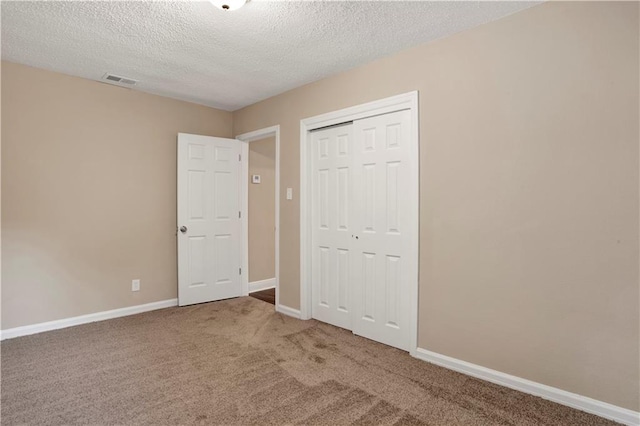 unfurnished bedroom with a textured ceiling, a closet, and carpet flooring