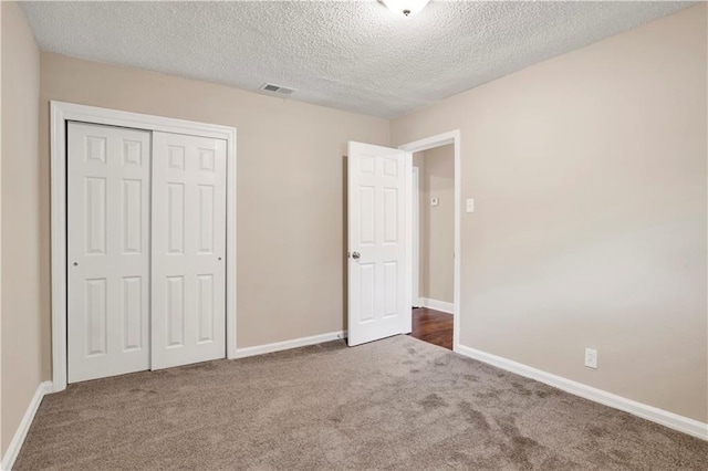 unfurnished bedroom with dark carpet, a closet, and a textured ceiling