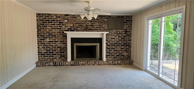 unfurnished living room with crown molding, brick wall, a brick fireplace, and carpet