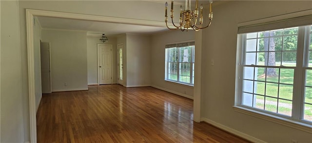 unfurnished room featuring dark wood-type flooring, ornamental molding, and a chandelier