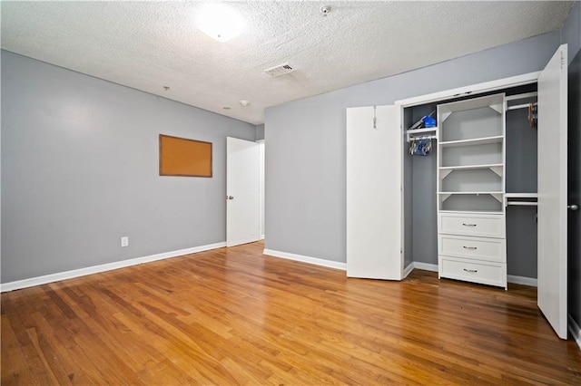 17714 Horseneck Rd, Bay Minette, AL 36507 - unfurnished bedroom featuring a closet, wood finished floors, a textured ceiling, visible vents, and baseboards