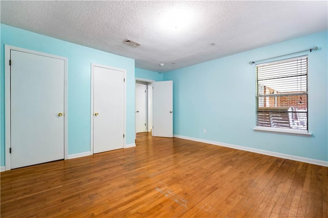 17714 Horseneck Rd, Bay Minette, AL 36507 - unfurnished bedroom with baseboards, visible vents, a textured ceiling, and wood finished floors