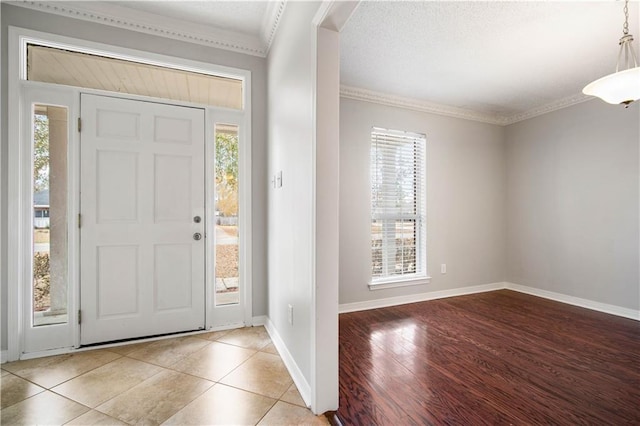 entrance foyer with ornamental molding, light wood-type flooring, and a wealth of natural light