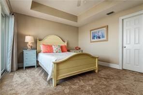 bedroom featuring ceiling fan, a tray ceiling, and carpet floors