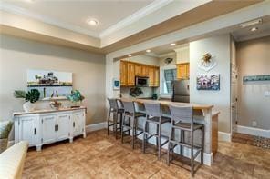 kitchen featuring ornamental molding, stainless steel appliances, kitchen peninsula, and a breakfast bar area