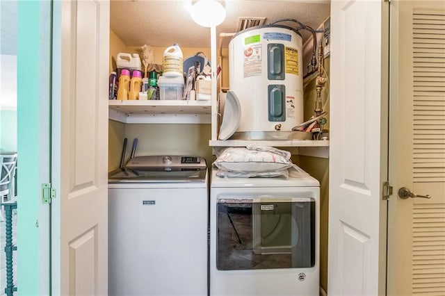 laundry room featuring washing machine and dryer, electric water heater, and a textured ceiling