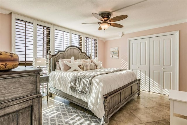 tiled bedroom with ceiling fan, crown molding, and a closet