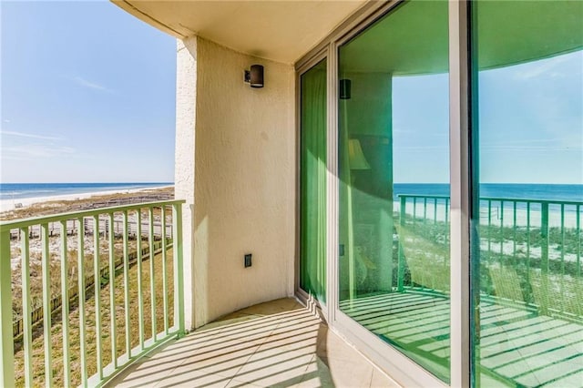 balcony with a water view and a view of the beach