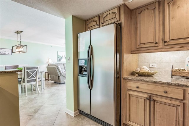 kitchen featuring tasteful backsplash, light stone counters, stainless steel refrigerator with ice dispenser, pendant lighting, and ornamental molding