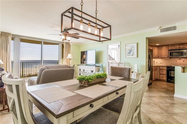 tiled dining area featuring a textured ceiling, ceiling fan with notable chandelier, and crown molding