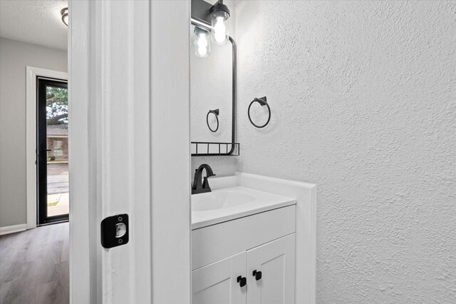 bathroom with hardwood / wood-style floors, vanity, and a textured ceiling