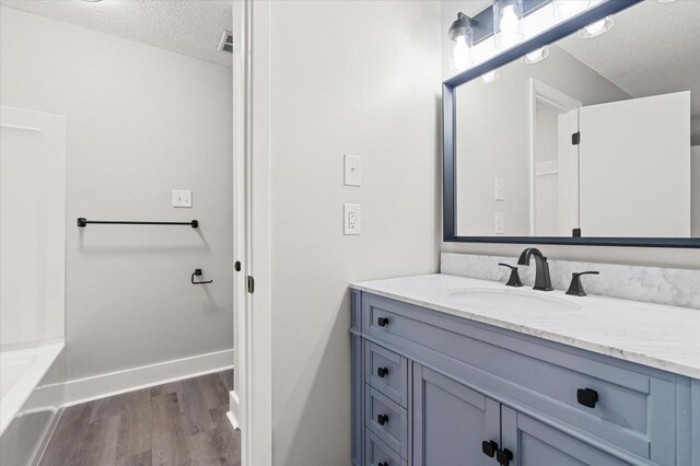 bathroom with hardwood / wood-style floors, vanity, and a textured ceiling