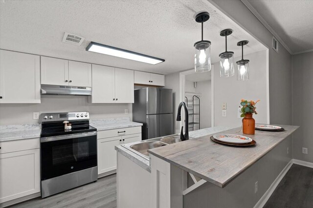 kitchen featuring hanging light fixtures, white cabinetry, light hardwood / wood-style floors, kitchen peninsula, and stainless steel appliances