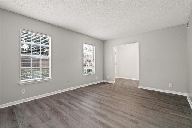 spare room featuring dark wood-type flooring and a textured ceiling