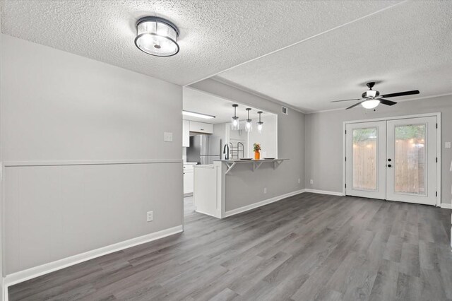 unfurnished living room with french doors, a textured ceiling, ceiling fan, and dark wood-type flooring