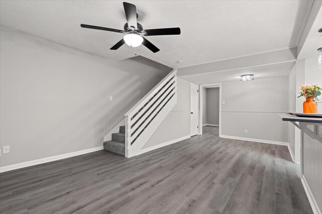 unfurnished living room with a textured ceiling, ceiling fan, and dark wood-type flooring