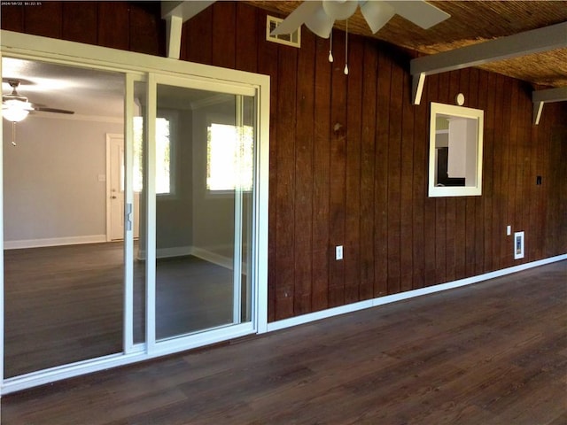 unfurnished room featuring wood walls, beam ceiling, ceiling fan, and dark hardwood / wood-style flooring