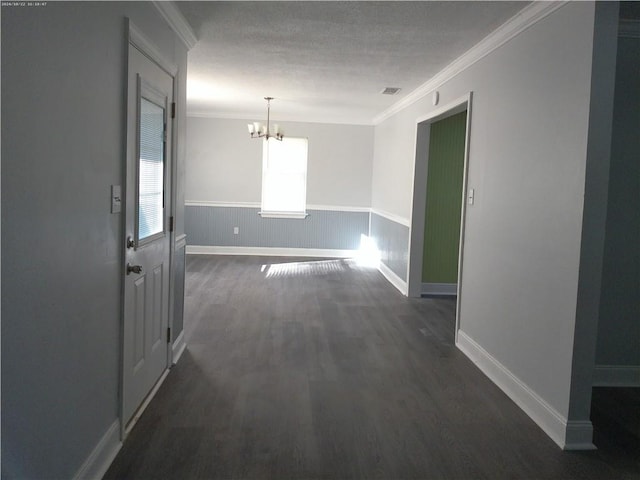 unfurnished dining area with dark wood-type flooring, crown molding, a textured ceiling, and a chandelier