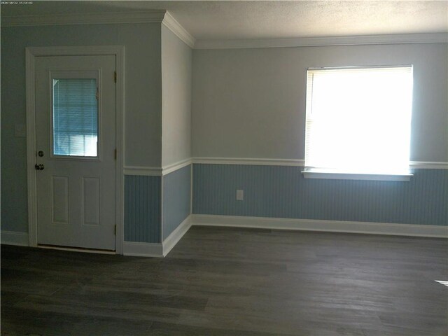 foyer entrance with dark wood-type flooring, ornamental molding, and a textured ceiling