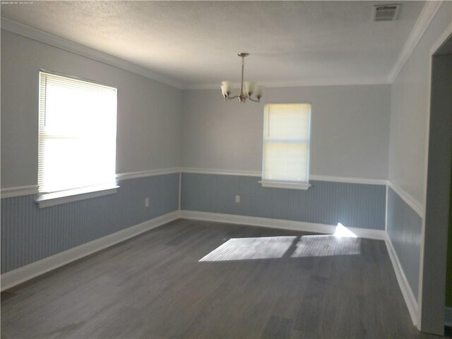 unfurnished room with crown molding, dark hardwood / wood-style floors, a chandelier, and a textured ceiling