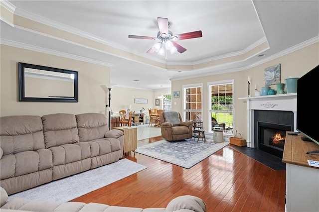 7115 Haleys Way, Theodore, AL 36582 - living area with a tray ceiling, ceiling fan, dark wood finished floors, a fireplace, and crown molding