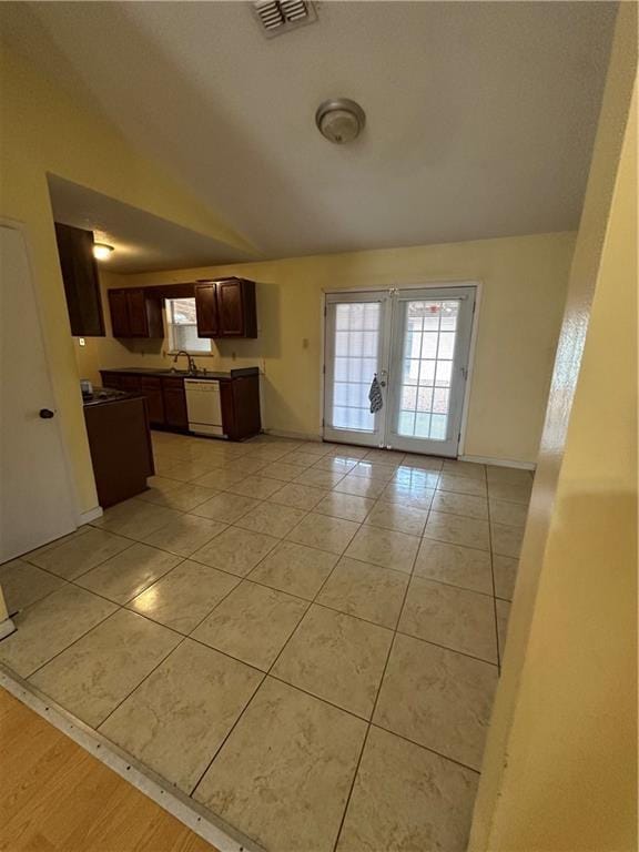 kitchen with light tile patterned floors, white dishwasher, a sink, visible vents, and dark brown cabinets