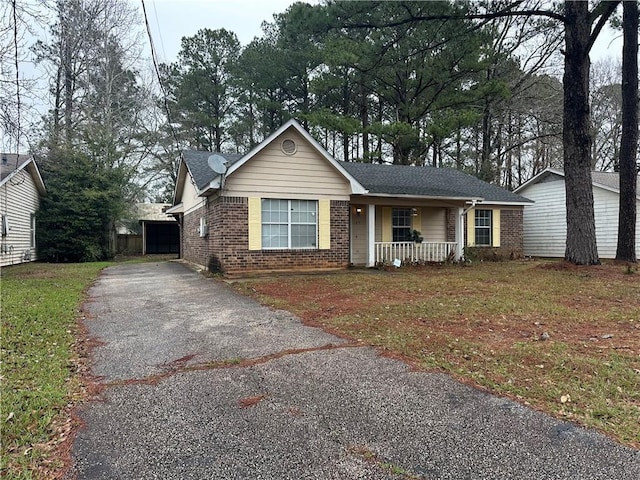 single story home featuring a porch, brick siding, driveway, and a front lawn