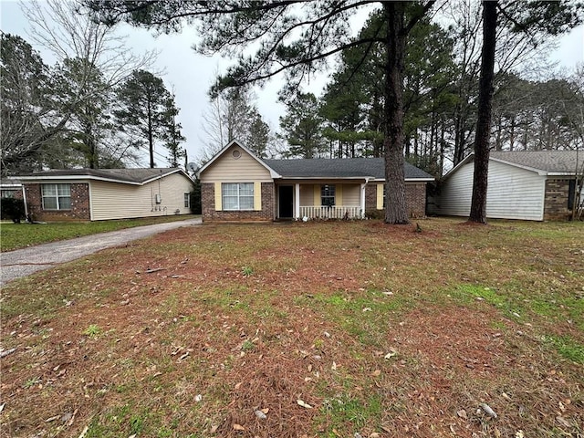 single story home featuring covered porch, a front lawn, and brick siding