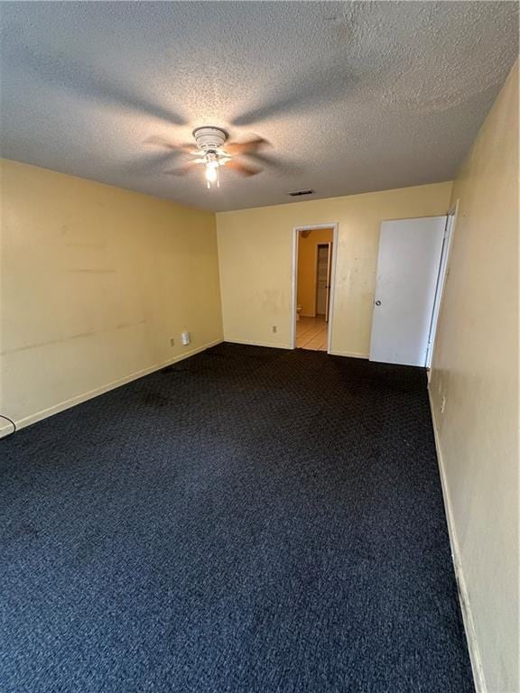 spare room featuring light carpet, a textured ceiling, visible vents, and a ceiling fan