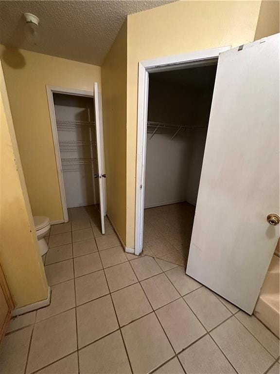 interior space featuring a spacious closet, a closet, a textured ceiling, and light tile patterned floors