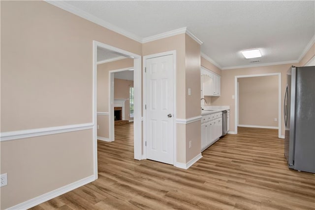 kitchen featuring light wood finished floors, light countertops, appliances with stainless steel finishes, and white cabinets