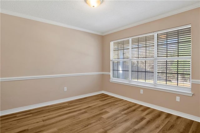 unfurnished room featuring ornamental molding, a textured ceiling, baseboards, and wood finished floors