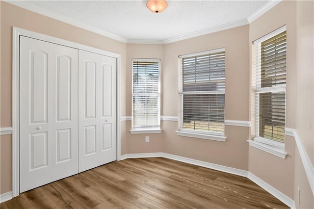 unfurnished bedroom featuring a textured ceiling, a closet, baseboards, and wood finished floors